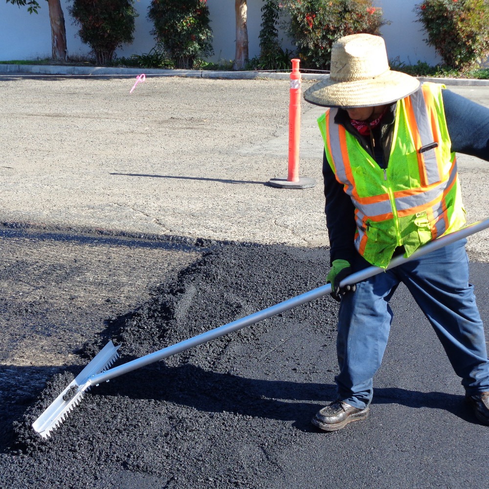 An operator using Surfa Slick's magnesium asphalt lutes to smooth asphalt