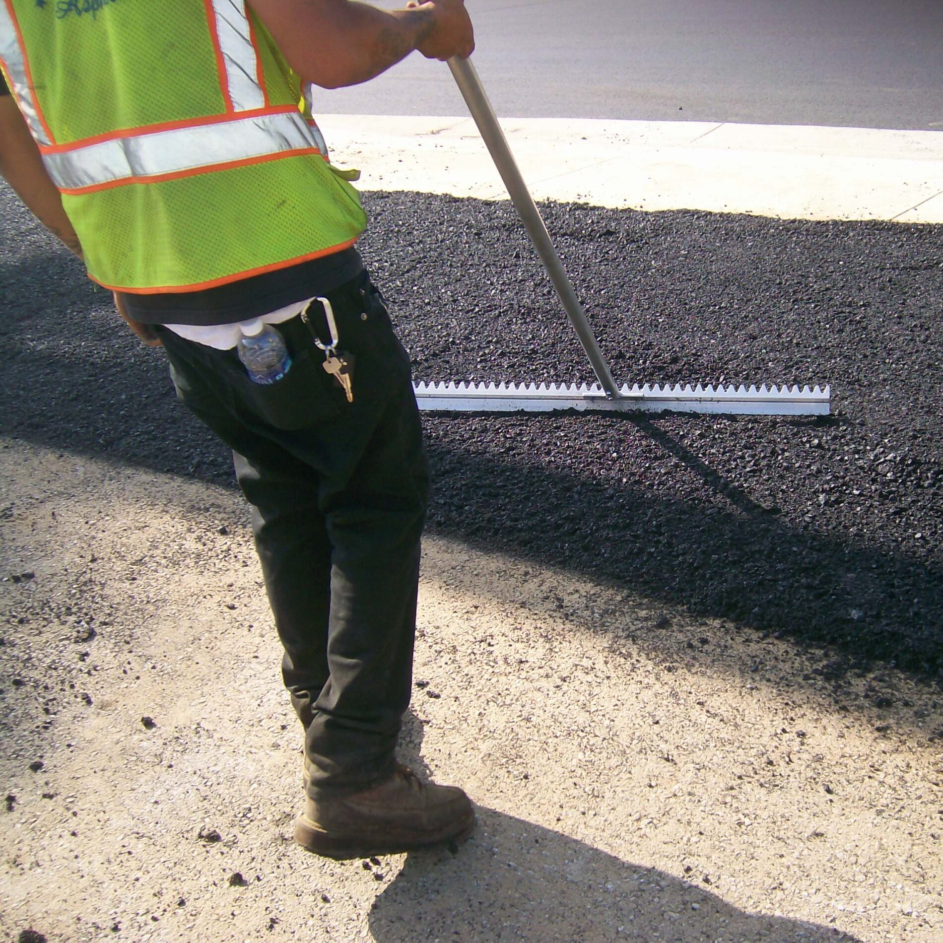 Operator using Surfa Slick's magnesium asphalt lute to smooth the surface of asphalt