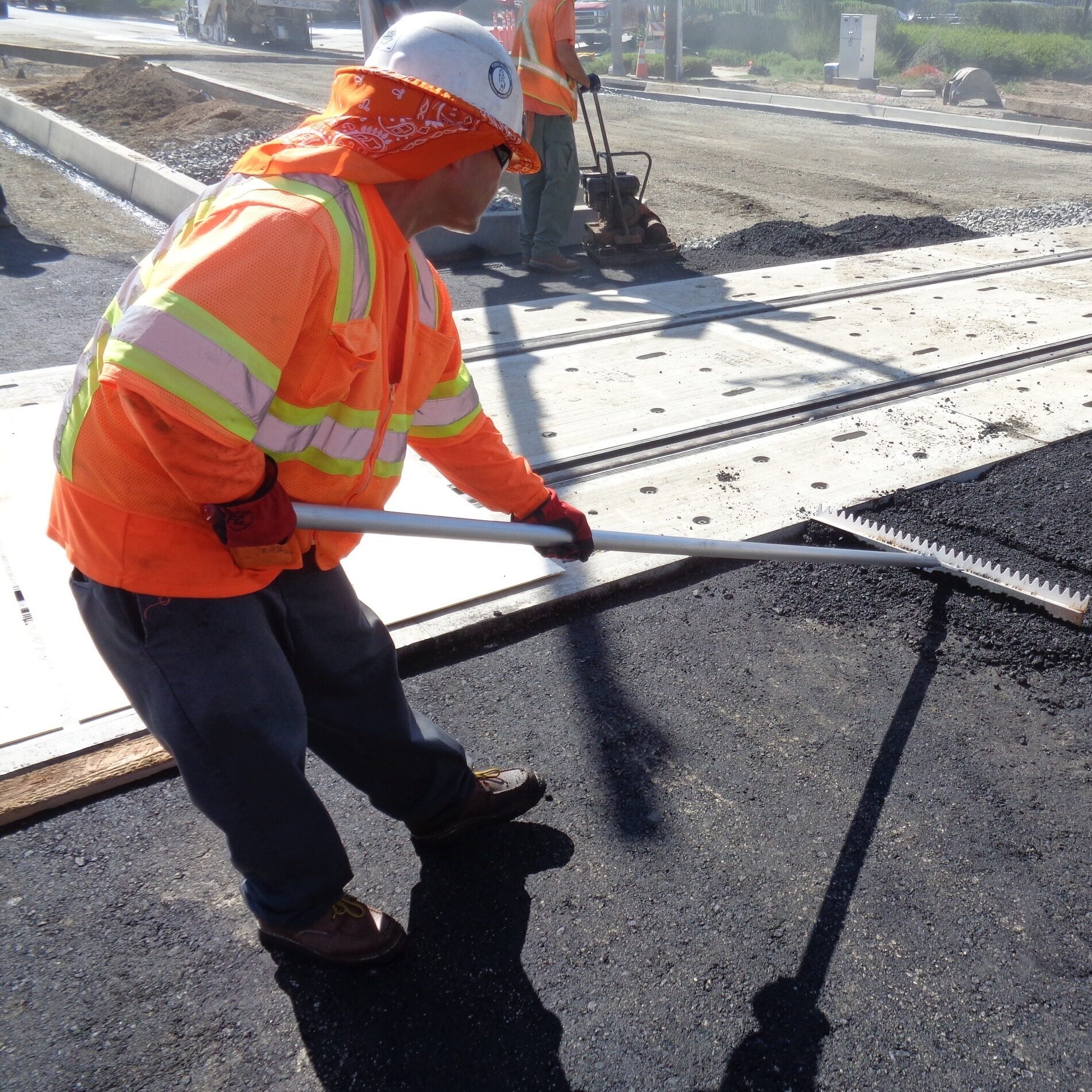 An operator using Surfa Slick's magnesium asphalt lutes to smooth asphalt