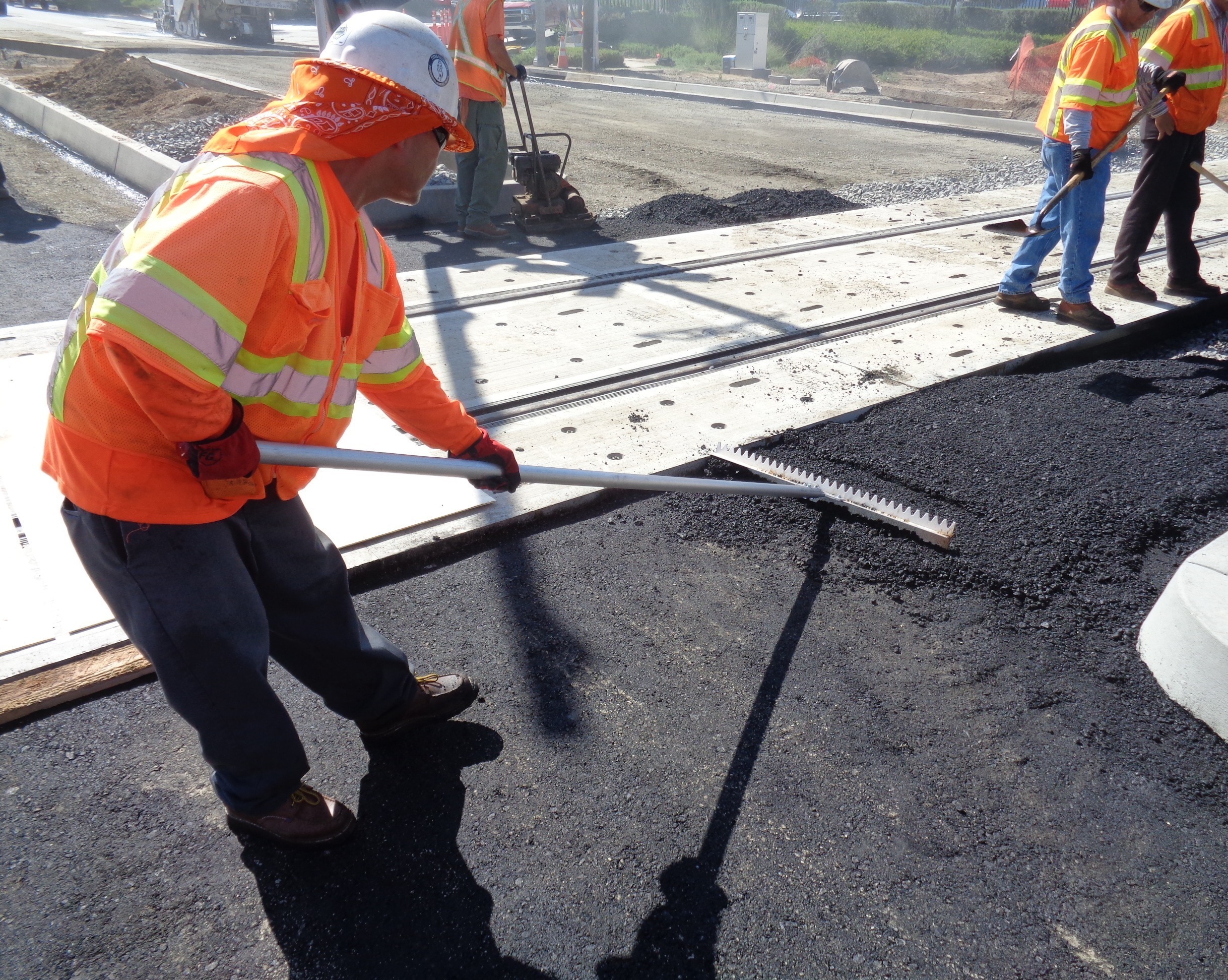 An operator using Surfa Slick's magnesium asphalt lutes to smooth asphalt