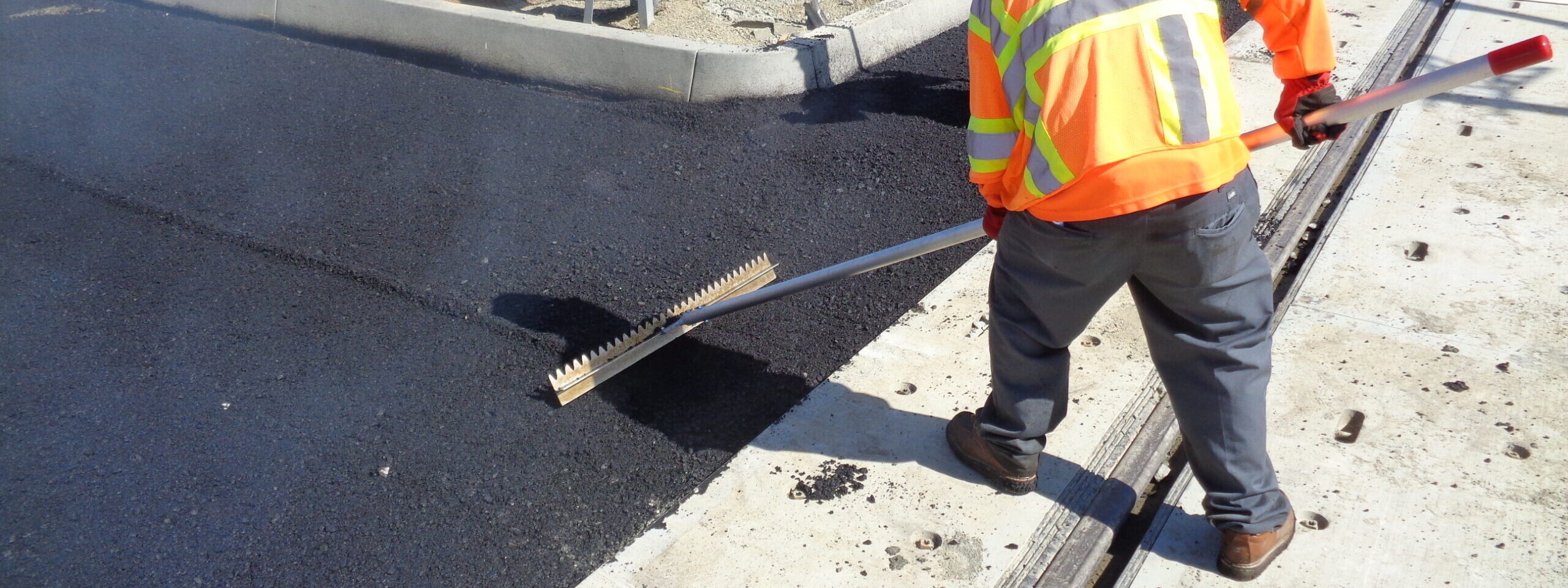 An operator using Surfa Slick's magnesium asphalt lutes to smooth asphalt