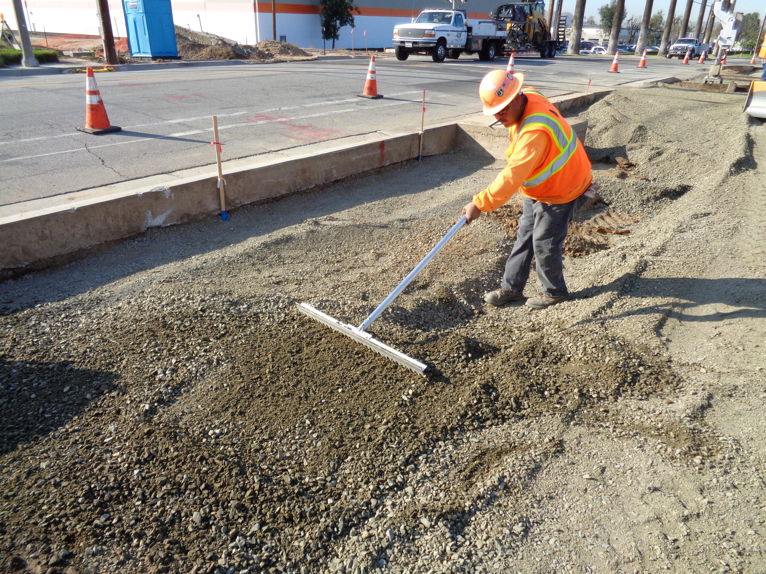 An operator using Surfa Slick's magnesium asphalt lutes to smooth dirt to prepare for side walk construction