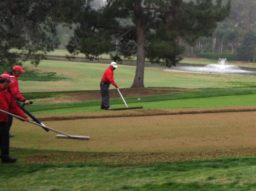 Workers using Surfa Slick's magnesium asphalt lute on a golf course